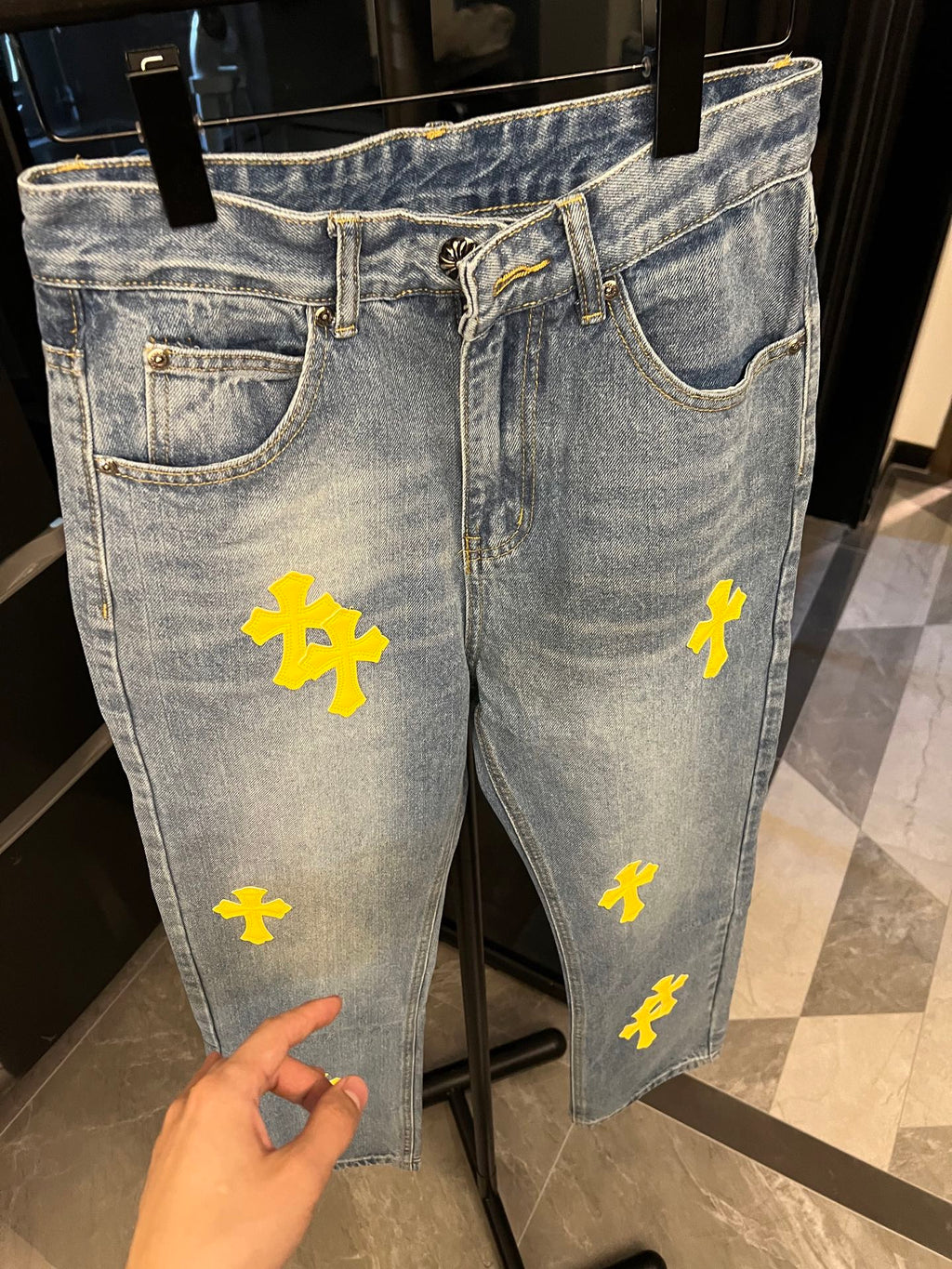 Light-wash denim jeans with yellow cross patches, front hip and thigh