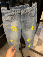Light-wash denim jeans with yellow cross patches, front hip and thigh