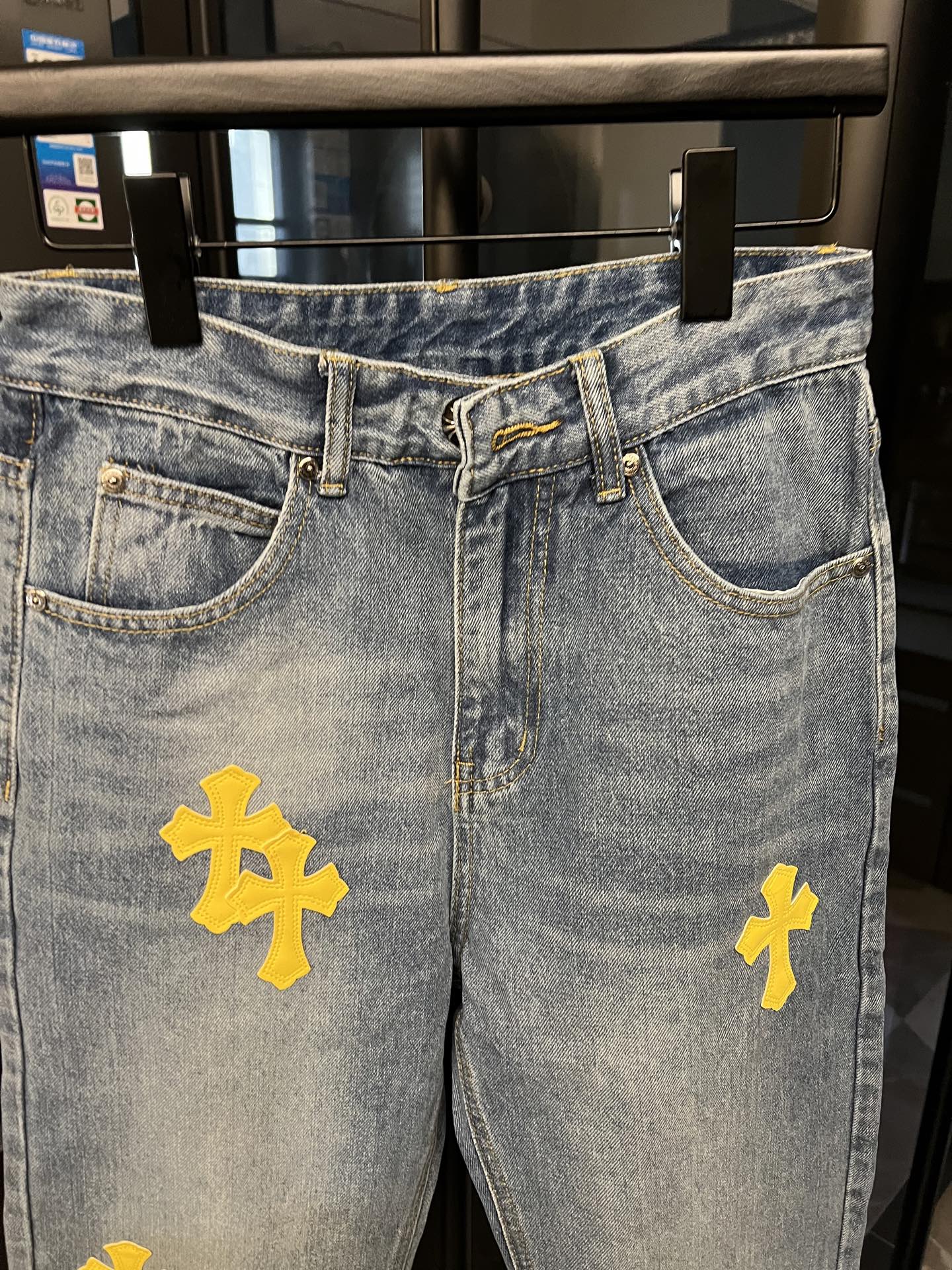 Light-wash denim jeans with yellow cross patches, waistband and pockets