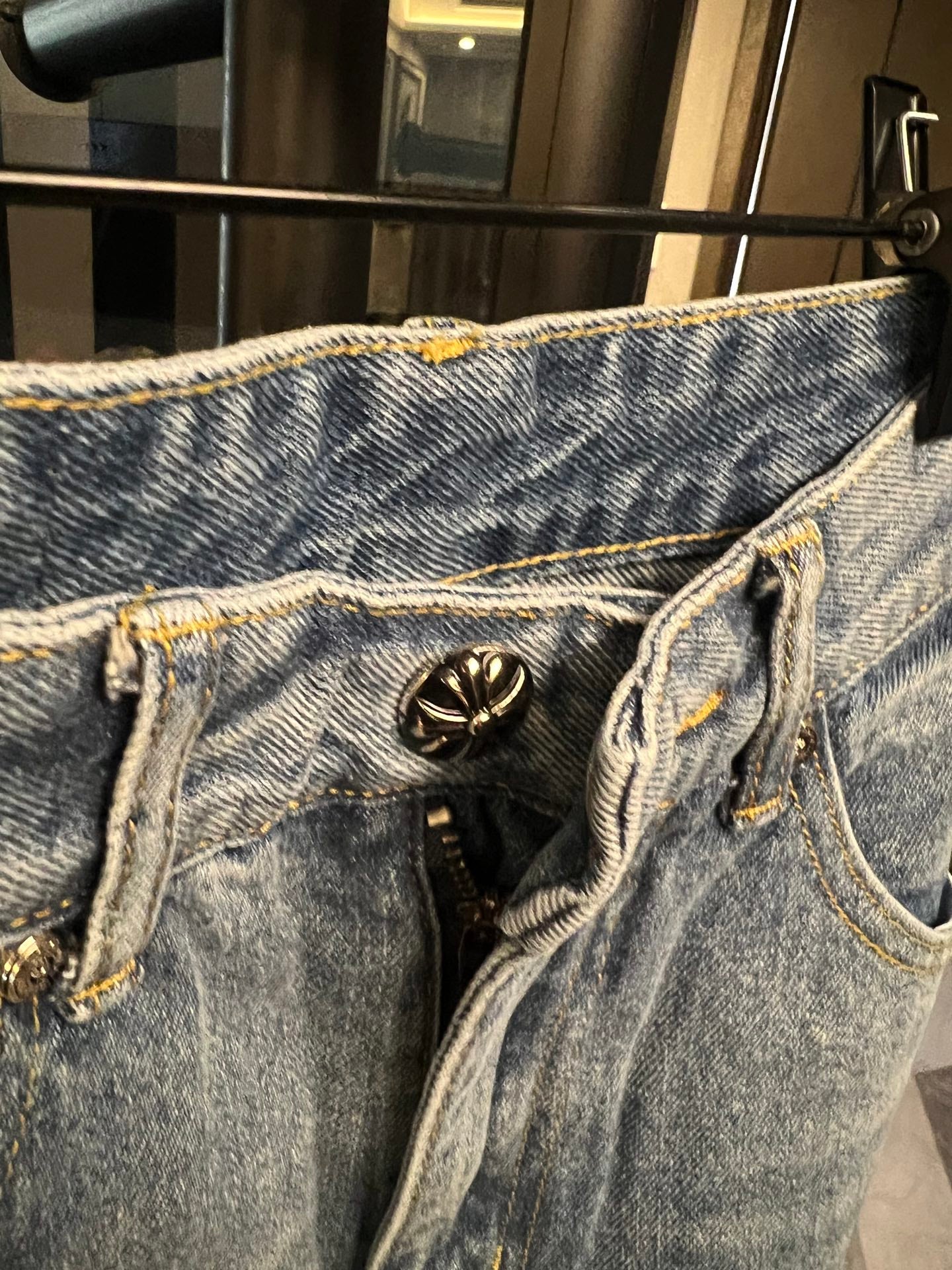 Light-wash denim jeans with stitched logo patch near zipper