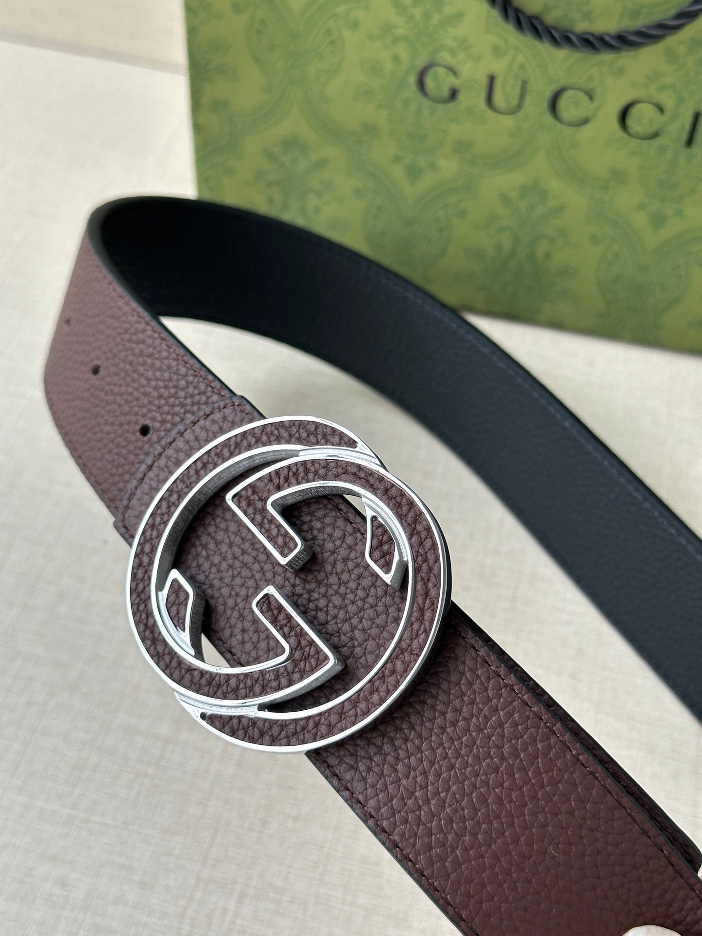 Brown leather belt with silver-tone interlocking G buckle, close-up view