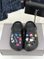 Black platform slide sneakers with multicolor charm accents and molded straps