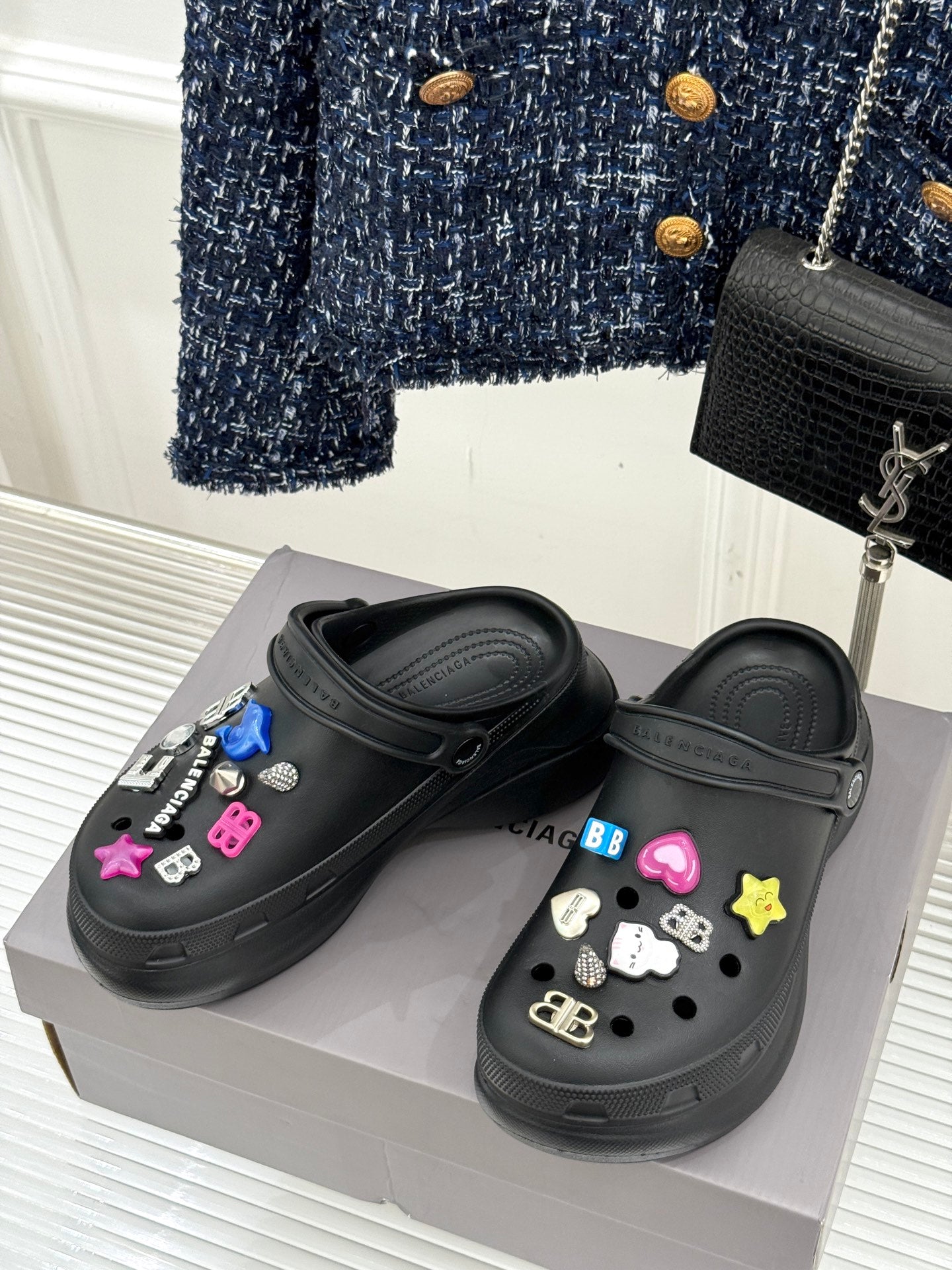 Black slide sneakers on display with colorful letter-and-star charm accents