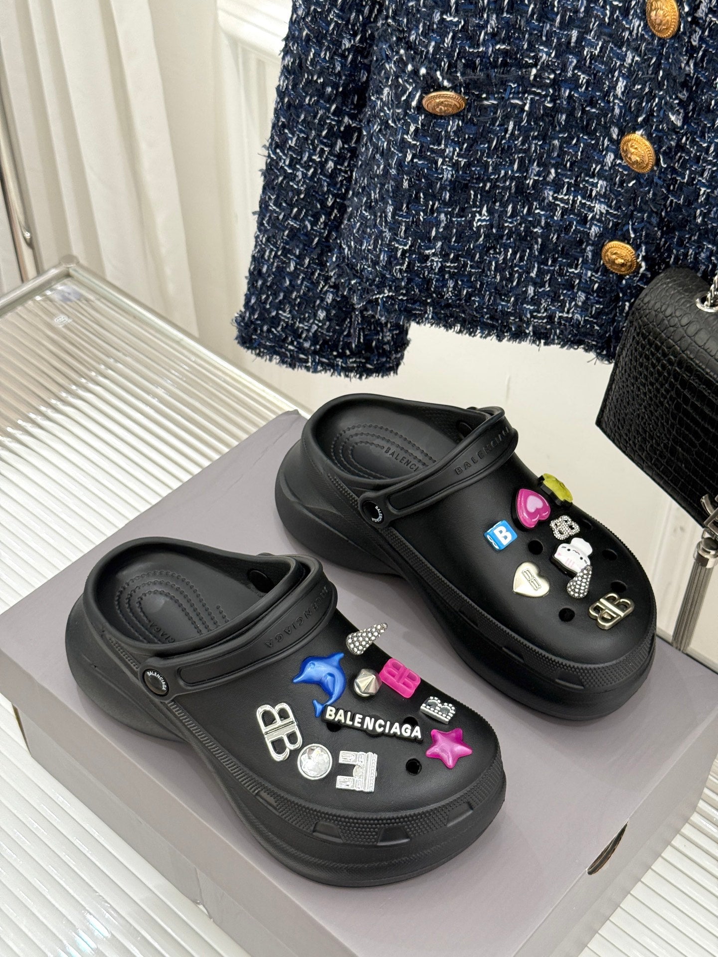 Black platform slide sneakers with colorful charm decorations and logo patches