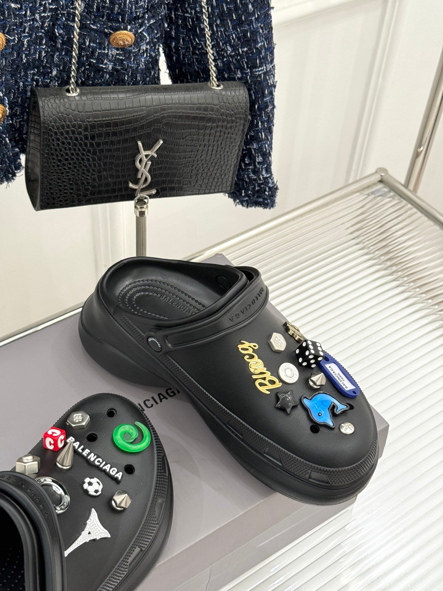 Balenciaga black slip-on clogs with studded charms, one shoe angled