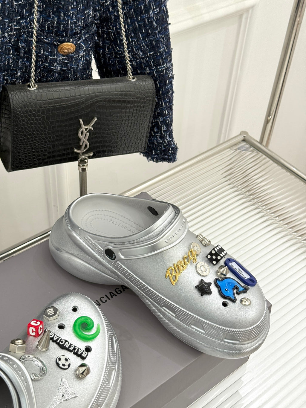 Pair of silver and white clog shoes with colorful charm decorations on top