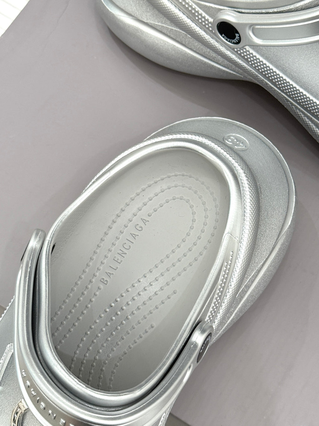 Silver clog with rounded toe and stitched insole edge visible