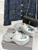 White platform clog shoes with colorful sticker charms and curved top