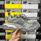 Gray Balenciaga lace-up sneaker with “B” logo and yellow accent overlays