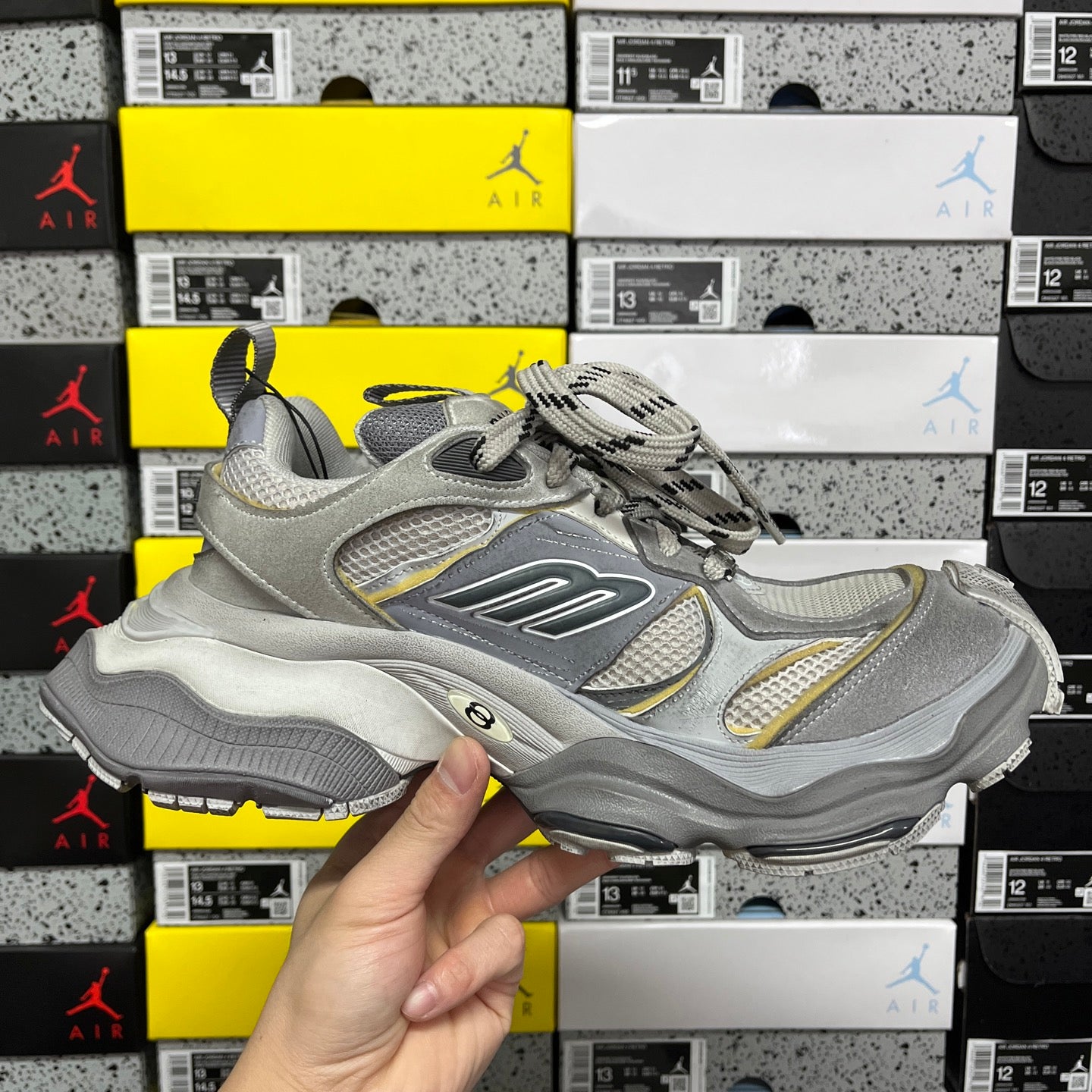 Gray Balenciaga lace-up sneaker with “B” logo and yellow accent overlays