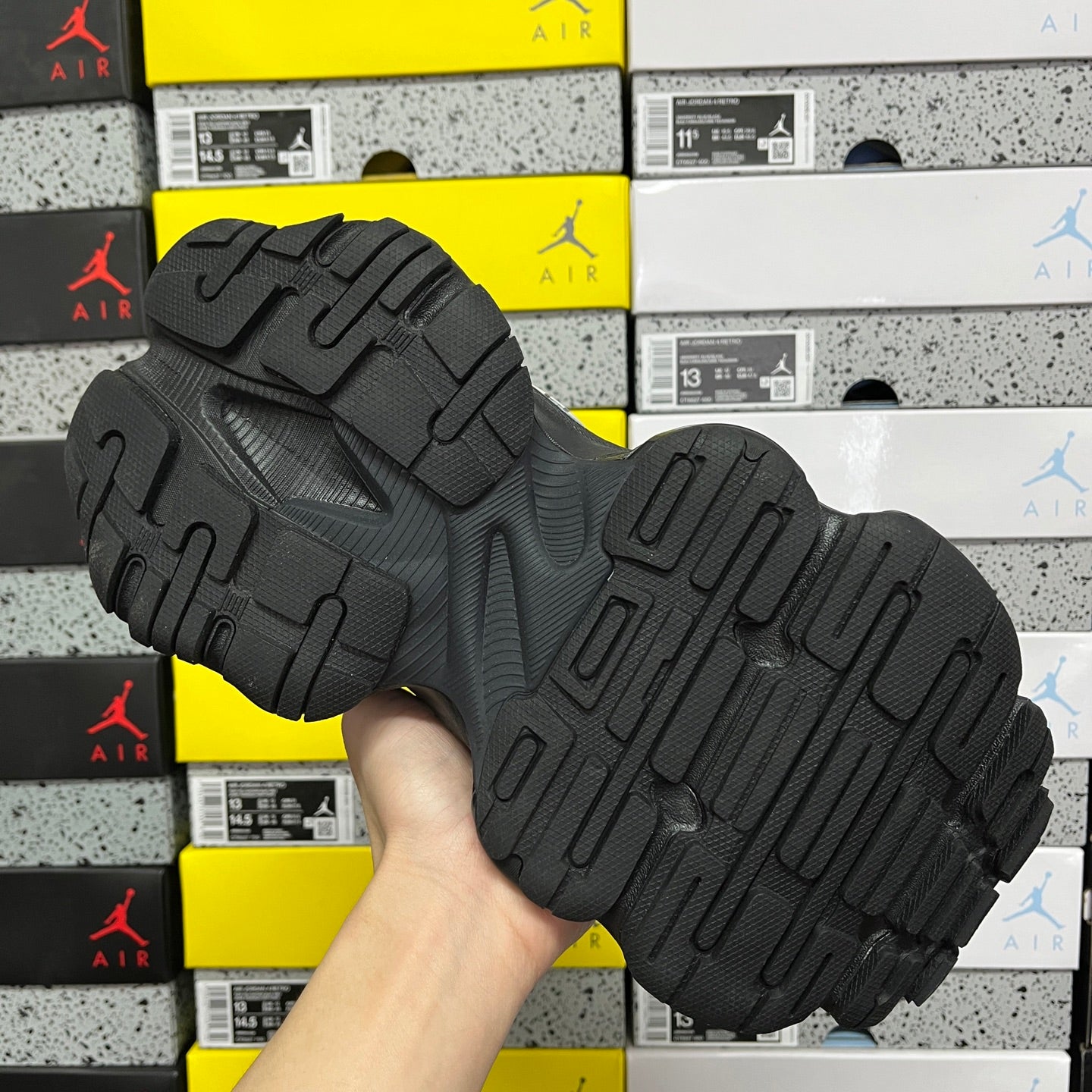 Black sneaker outsole view with raised traction tread and chunky rubber sole