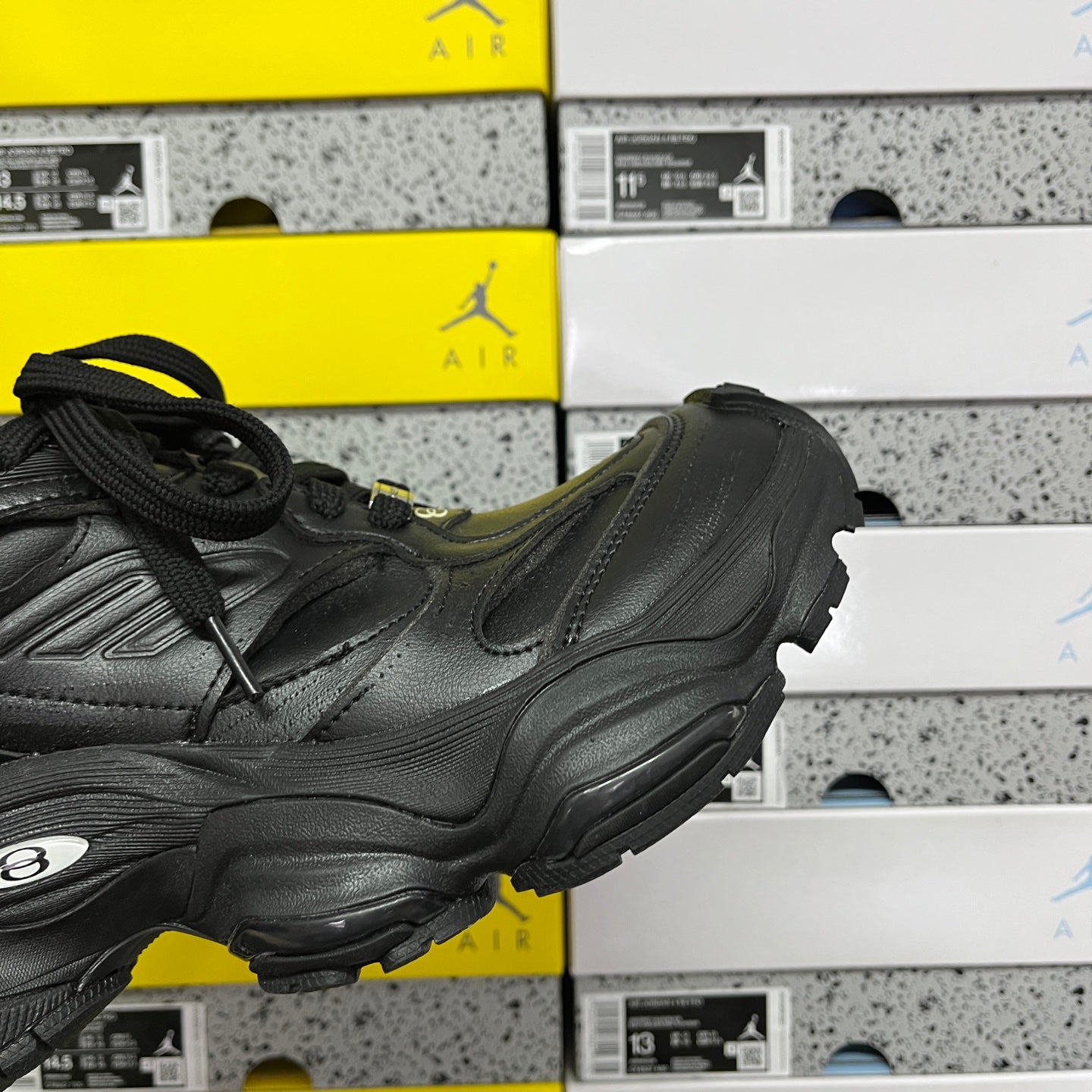 Black leather sneaker with side overlays, thick midsole, and lace-up closure