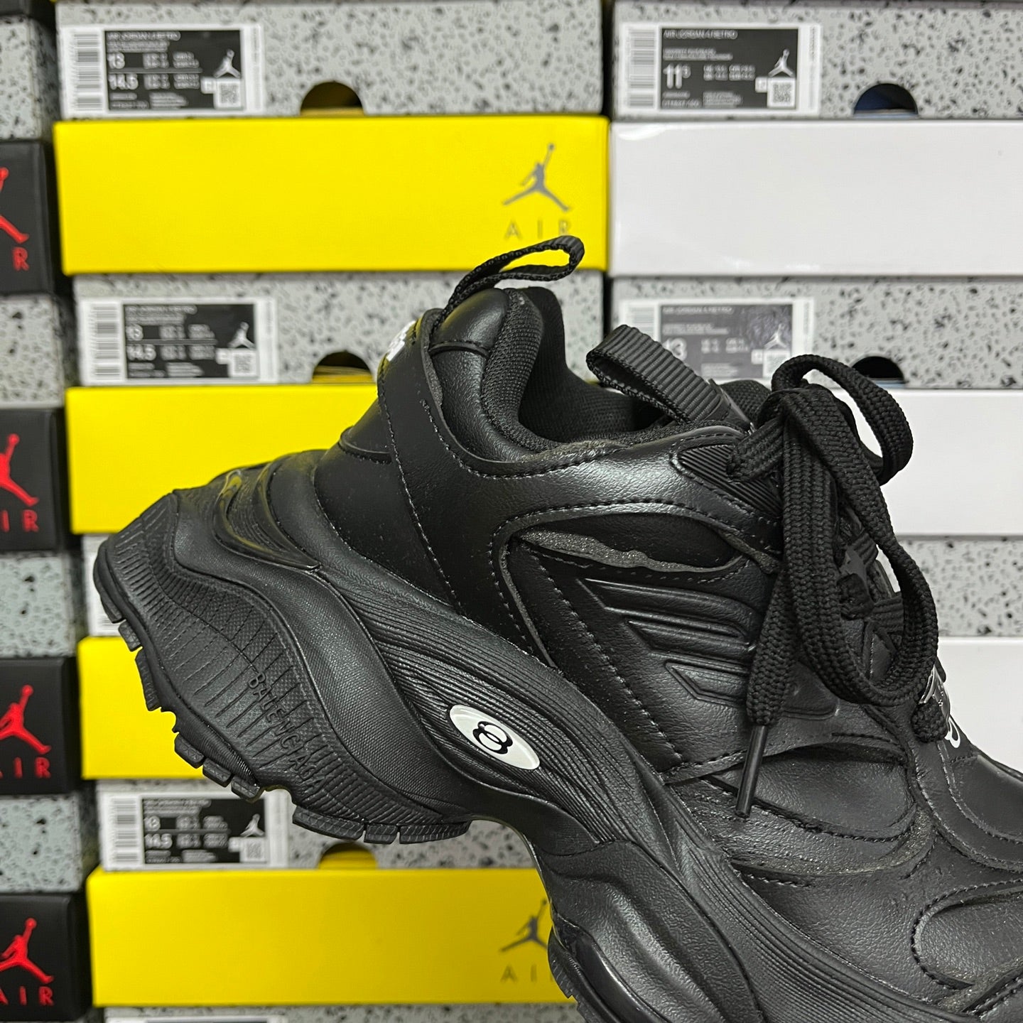 Black lace-up sneakers with textured side panels and oval logo on the sole