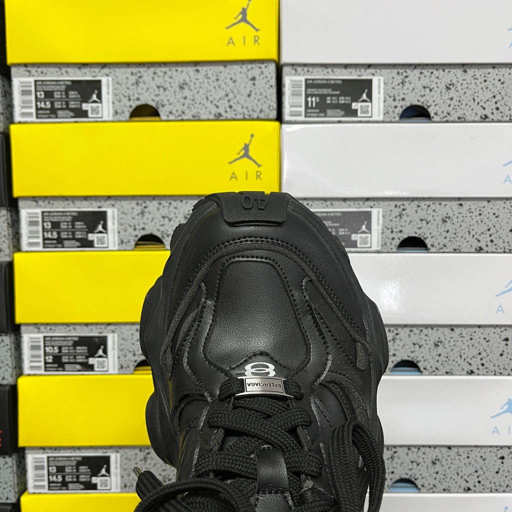 Black sneakers front view with lace-up eyelets and padded tongue label detail