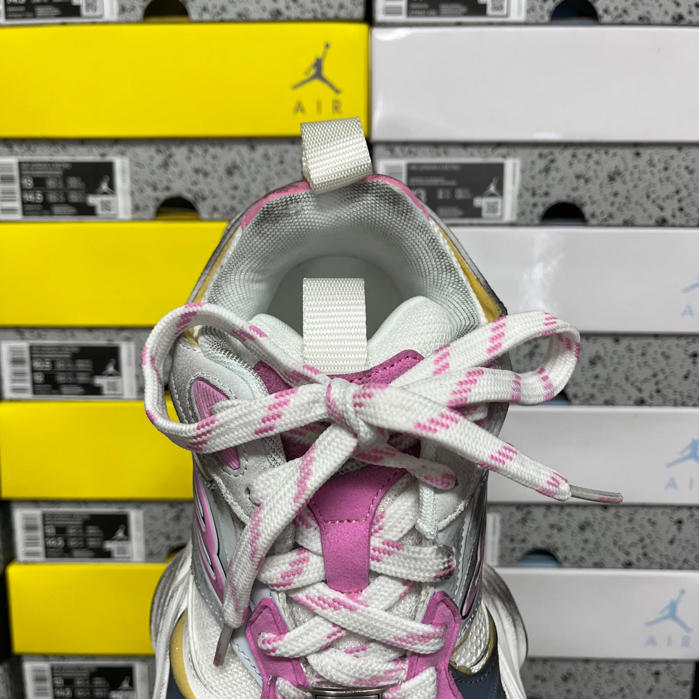 Lace and tongue view of silver and pink sneaker with woven collar label