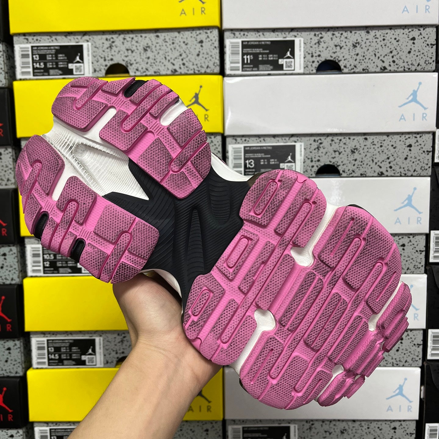 Outsole view of pink and dark sneaker with textured tread pattern