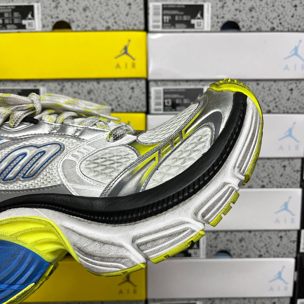 Side view of silver sneaker with blue and neon yellow-green details and black sole edge
