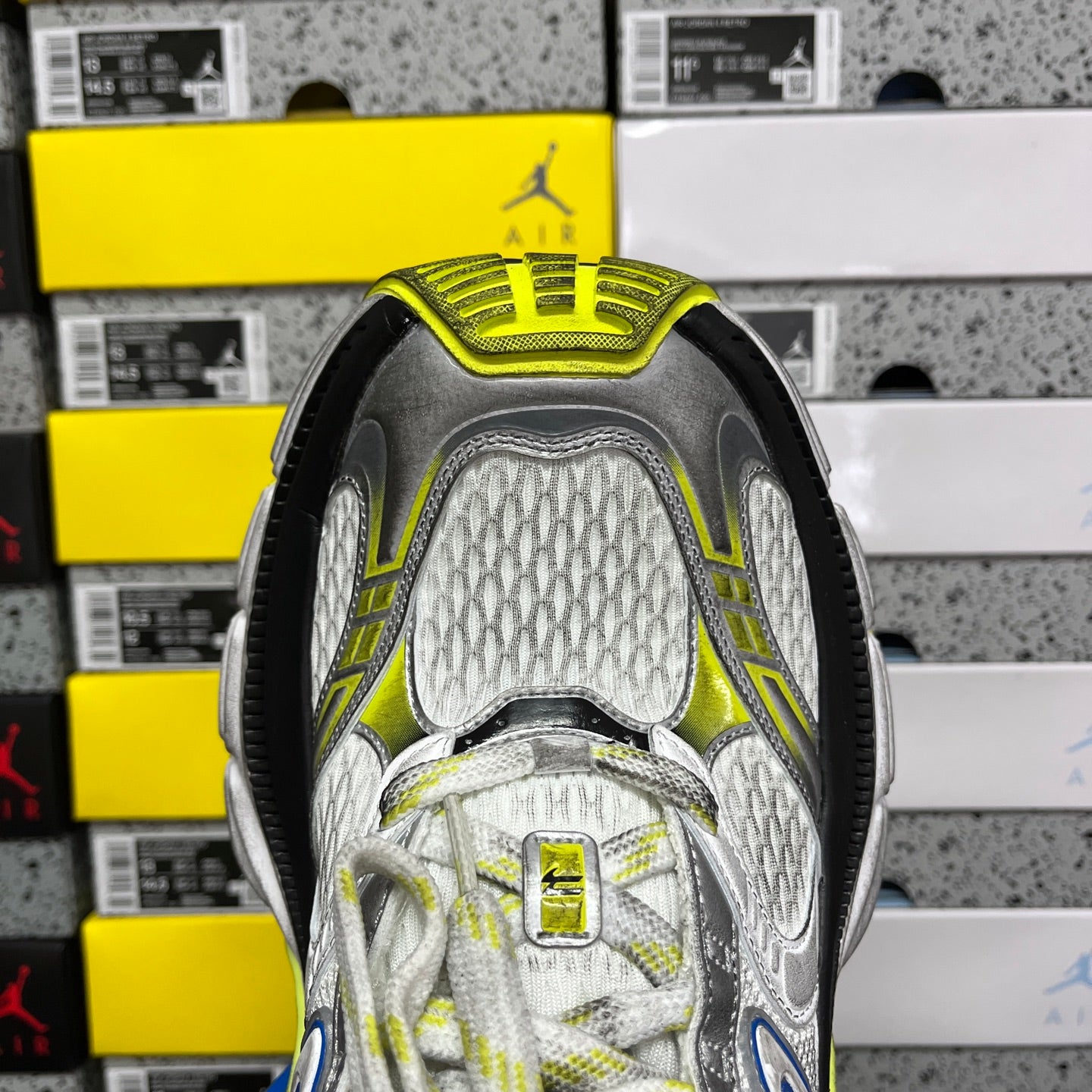 Rear view of gray sneaker with neon yellow-green collar and textured mesh panels