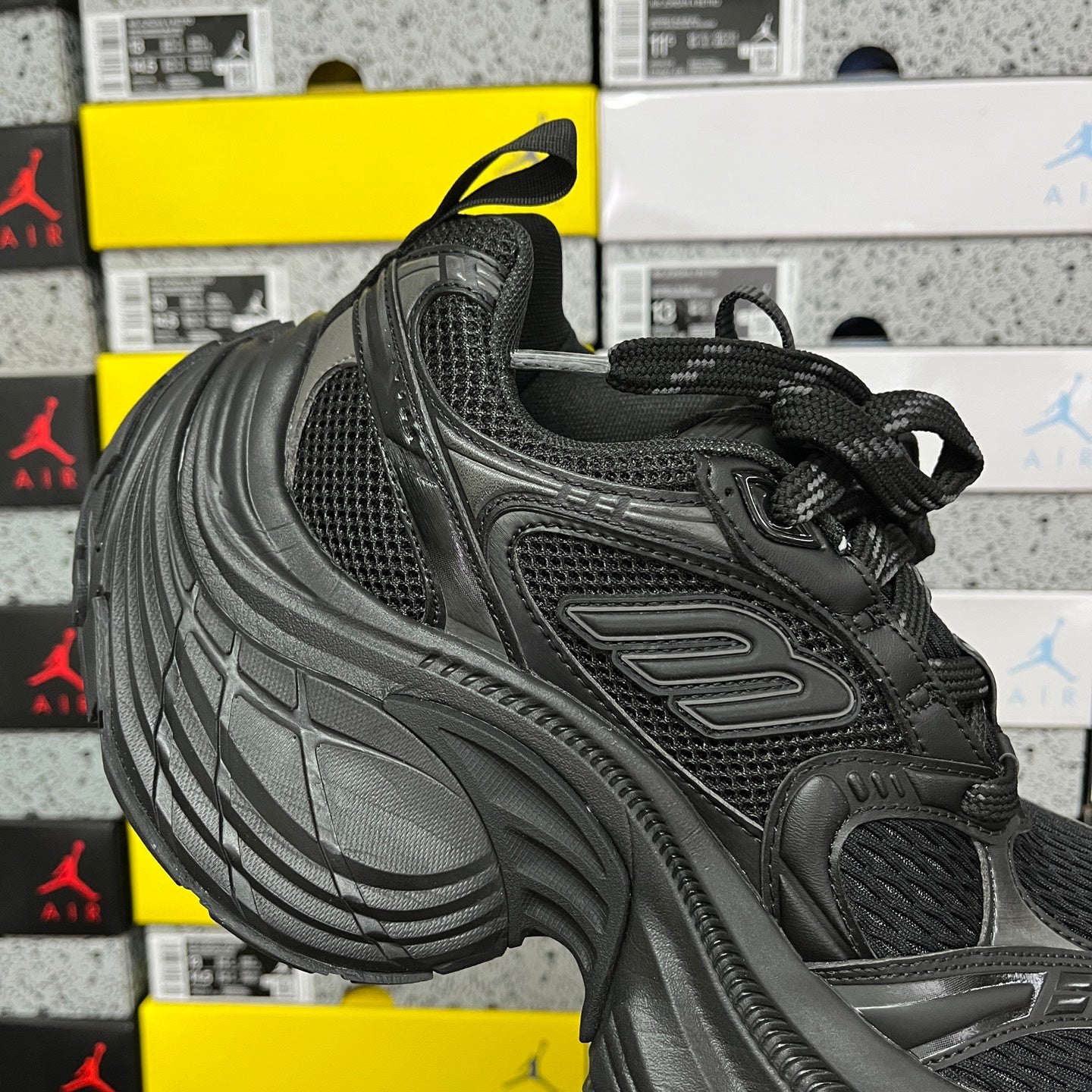 Black Balenciaga unisex sneaker, quarter view with mesh upper, lace-up, and thick tread sole