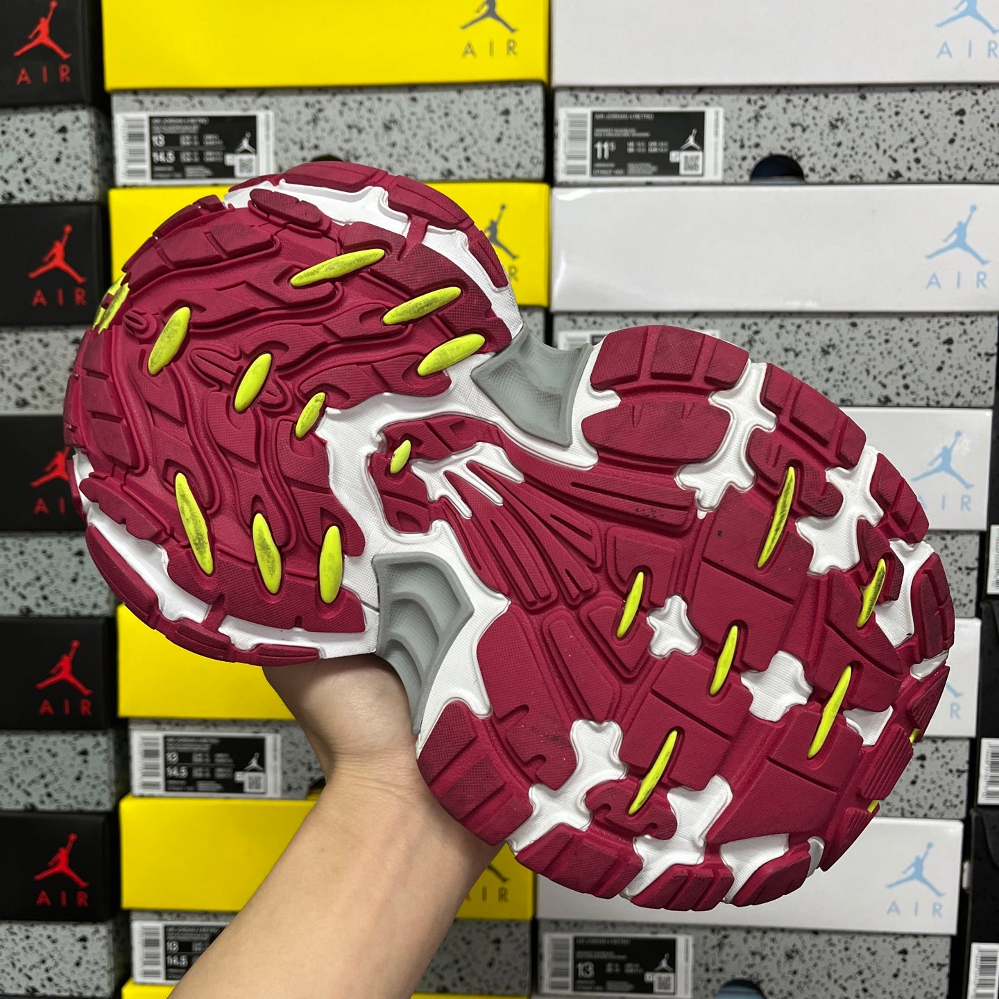 Silver and burgundy sneaker outsole with red traction pattern and neon green accents