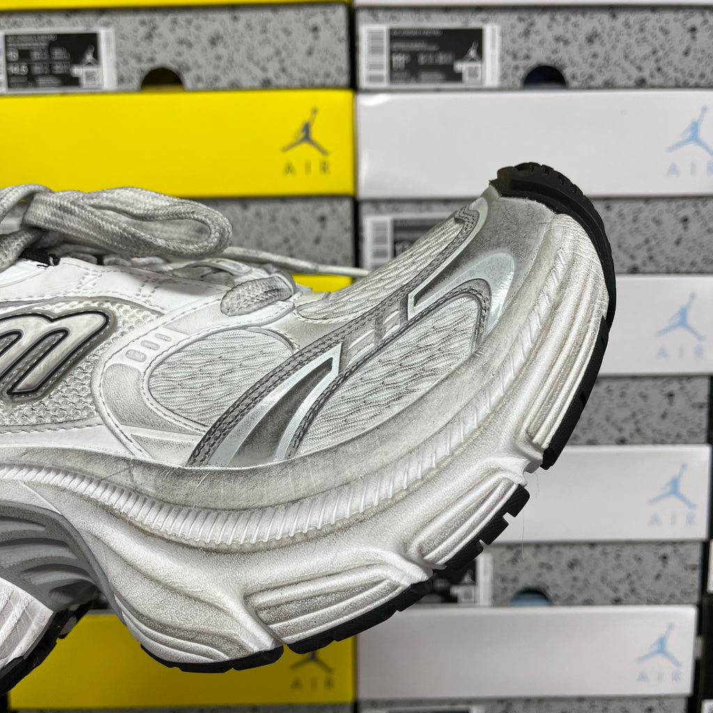 Silver running shoe side view with molded tread sole and black heel trim