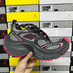 Three-quarter view of black and gray running shoes with pink accents and lace-up top.