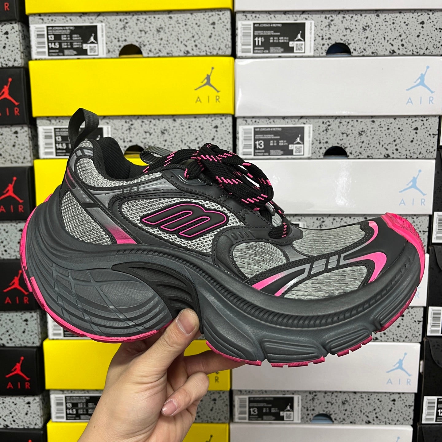 Black and gray running shoes with pink accents, mesh panels, and lace-up closure.