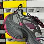 Black and gray mesh running shoe with pink logo patch and multicolor lace-up.