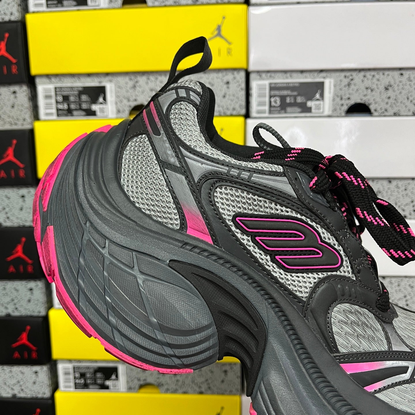 Black and gray mesh running shoe with pink logo patch and multicolor lace-up.