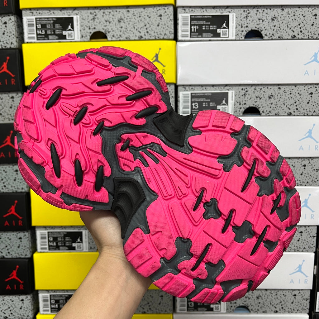 Rubber outsole of black and pink running shoe with deep traction tread.