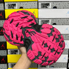 Rubber outsole of black and pink running shoe with deep traction tread.