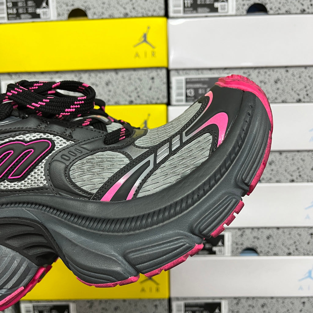 Side profile of black and gray running shoe with pink outsole edge and lace detail.