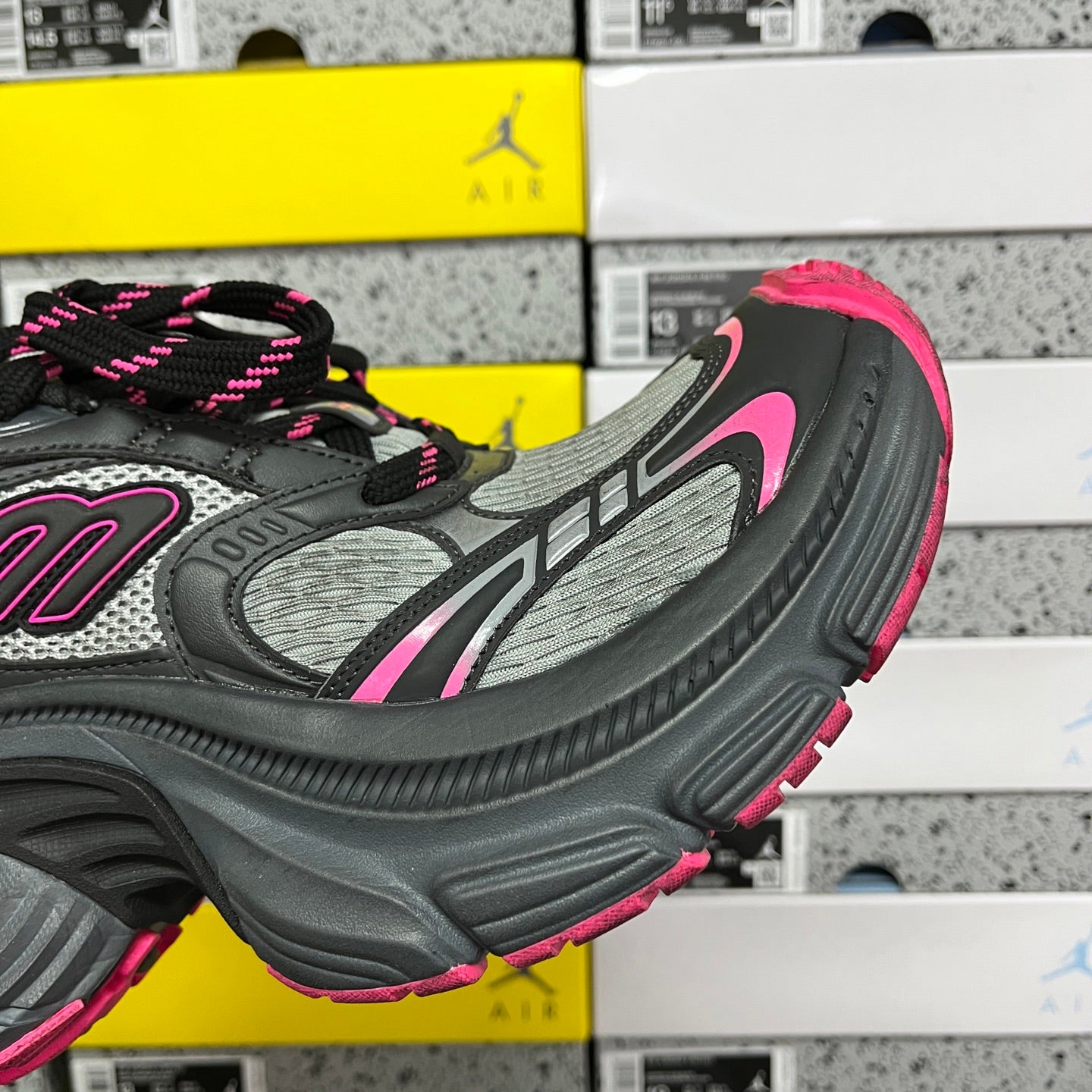 Side profile of black and gray running shoe with pink outsole edge and lace detail.