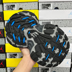 Outsole view of black sneaker with gray tread and blue traction pods