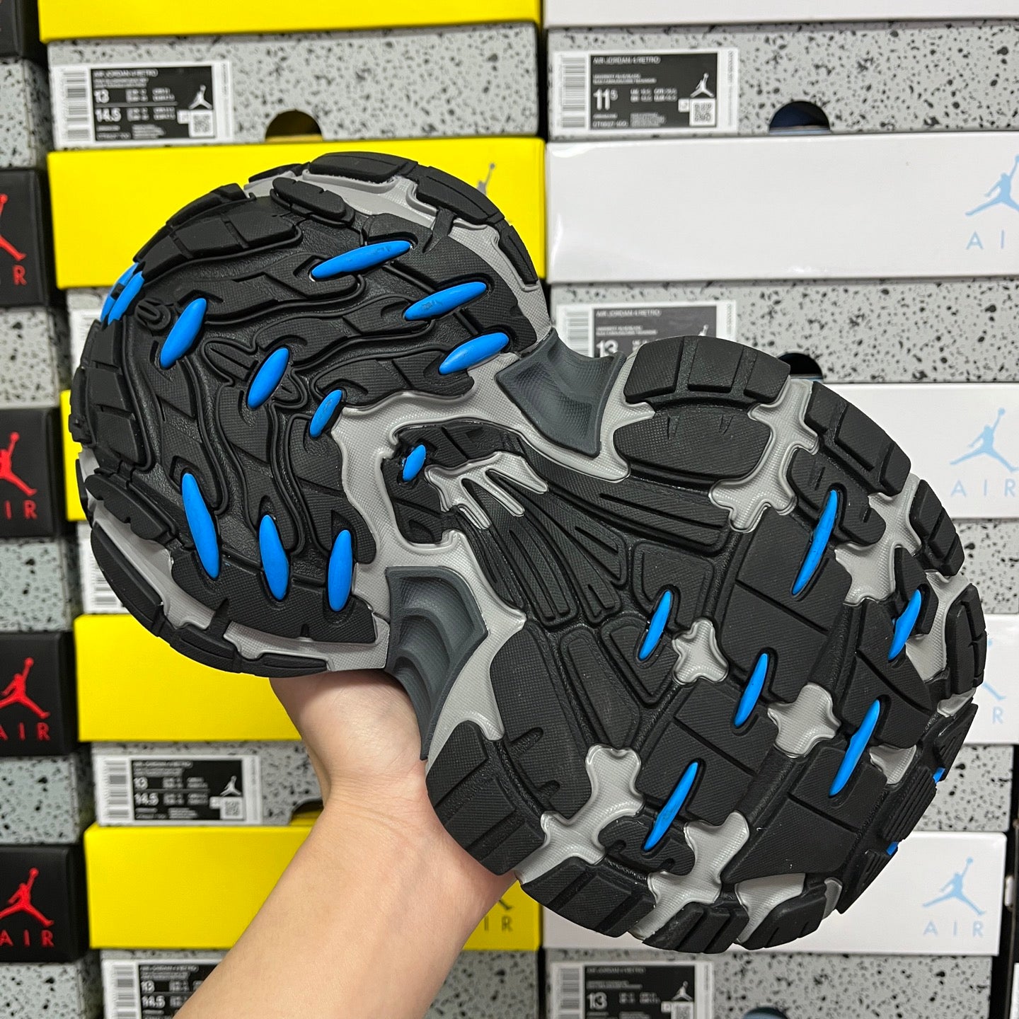 Outsole view of black sneaker with gray tread and blue traction pods