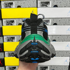 Heel view of black sneaker with blue tread accents and green midsole edge