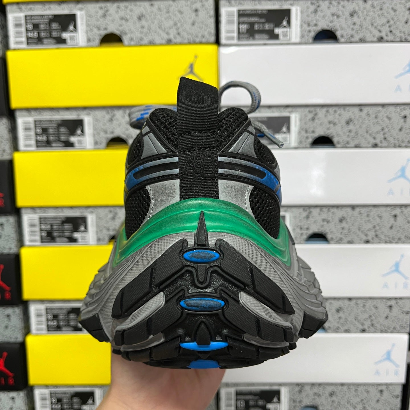 Heel view of black sneaker with blue tread accents and green midsole edge