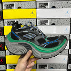 Chunky black sneaker with gray sole, blue accents, green trim, and lace-up upper