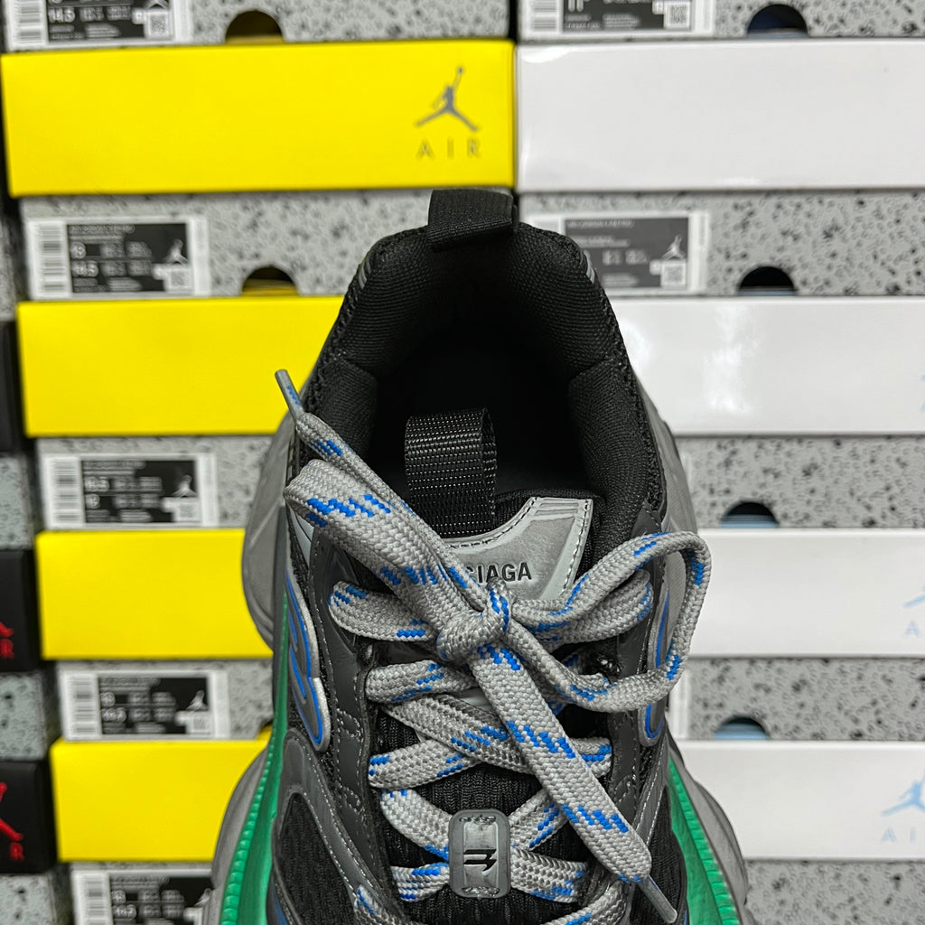 Front view of black sneaker with blue-and-gray laces and green-trimmed midsole