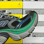 Side view of black sneaker with blue accents, green midsole trim, and textured gray outsole