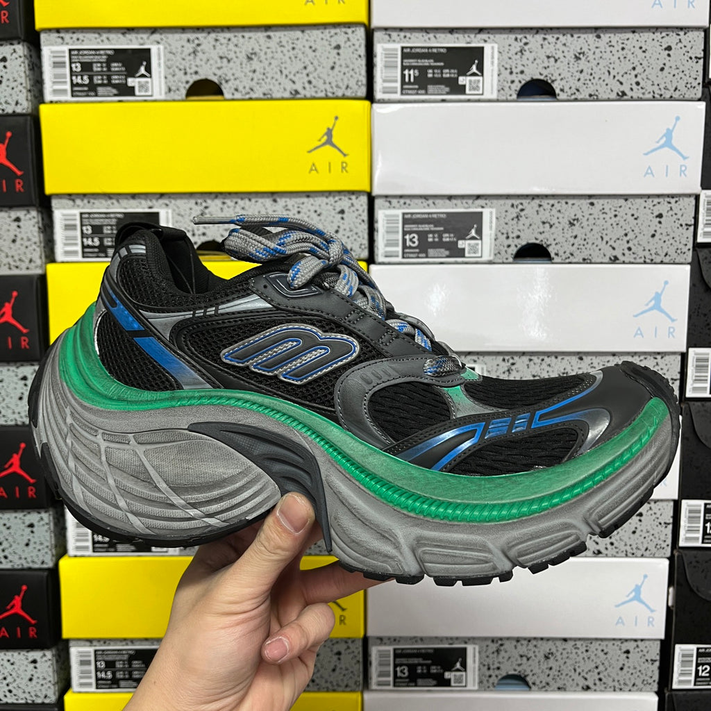 Lace-up black sneaker with blue details, green midsole trim, and gray molded outsole