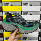 Lace-up black sneaker with blue details, green midsole trim, and gray molded outsole