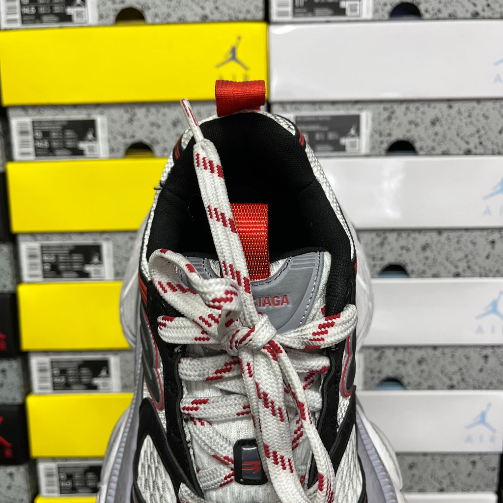 Black sneaker heel with red collar strap, white-and-red laces, and mesh overlay