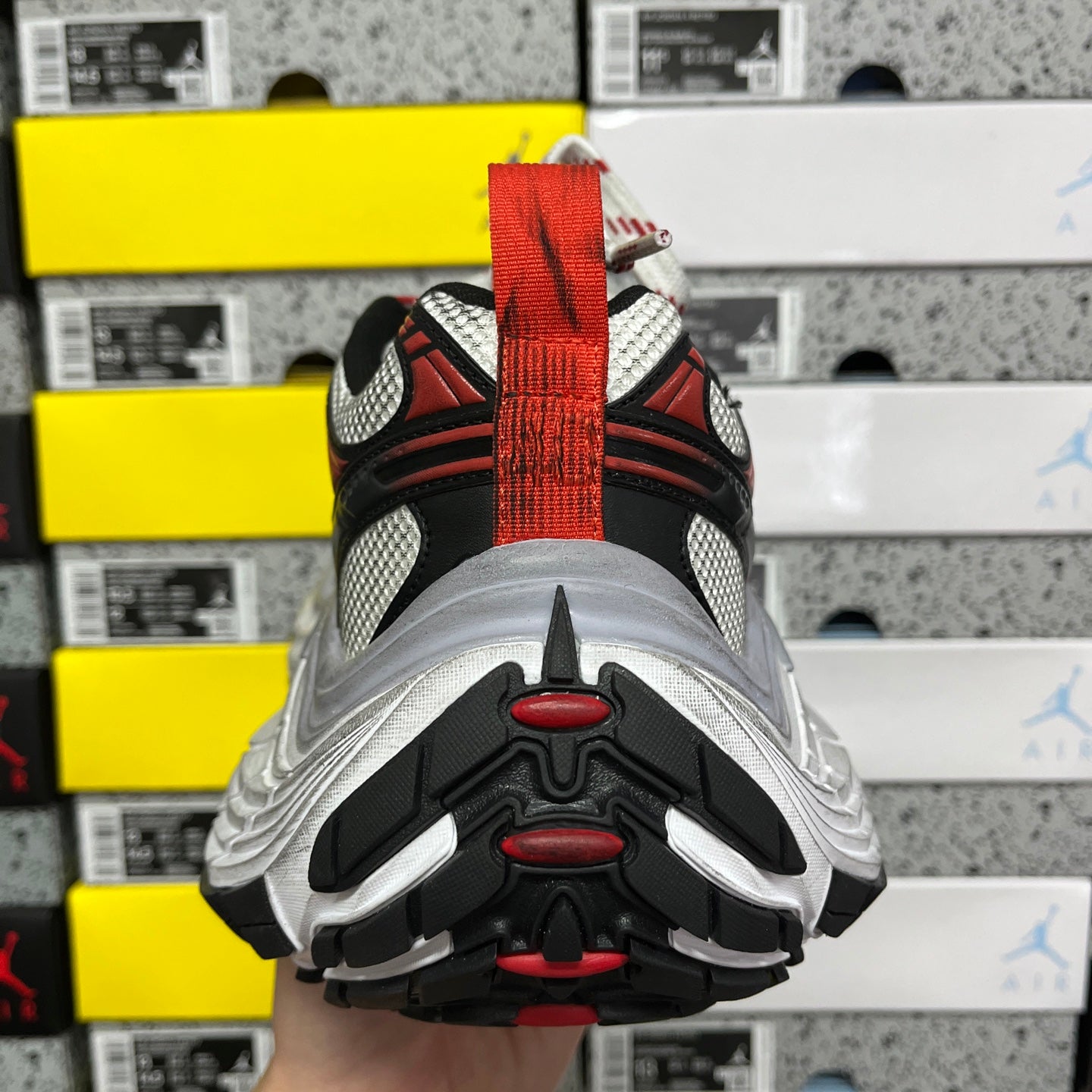 Sneaker outsole underside with molded tread and red details on black and gray rubber