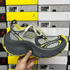 Chunky lace-up sneaker in dark gray, light gray, and neon yellow, held upright.