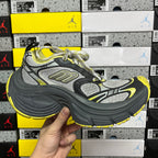 Front side view lace-up sneaker in dark gray, silver-gray, and neon yellow trim.