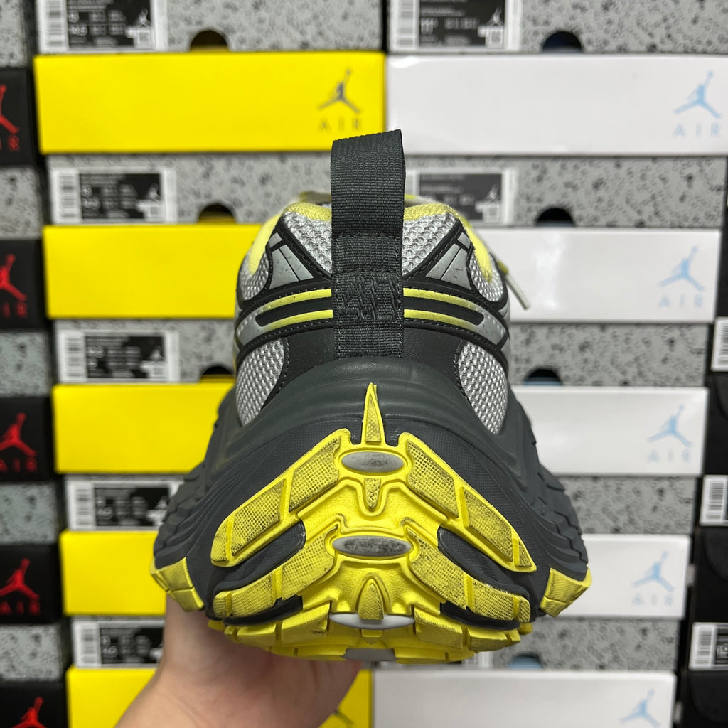 Back view sneaker with neon yellow tread and gray upper and black strap.