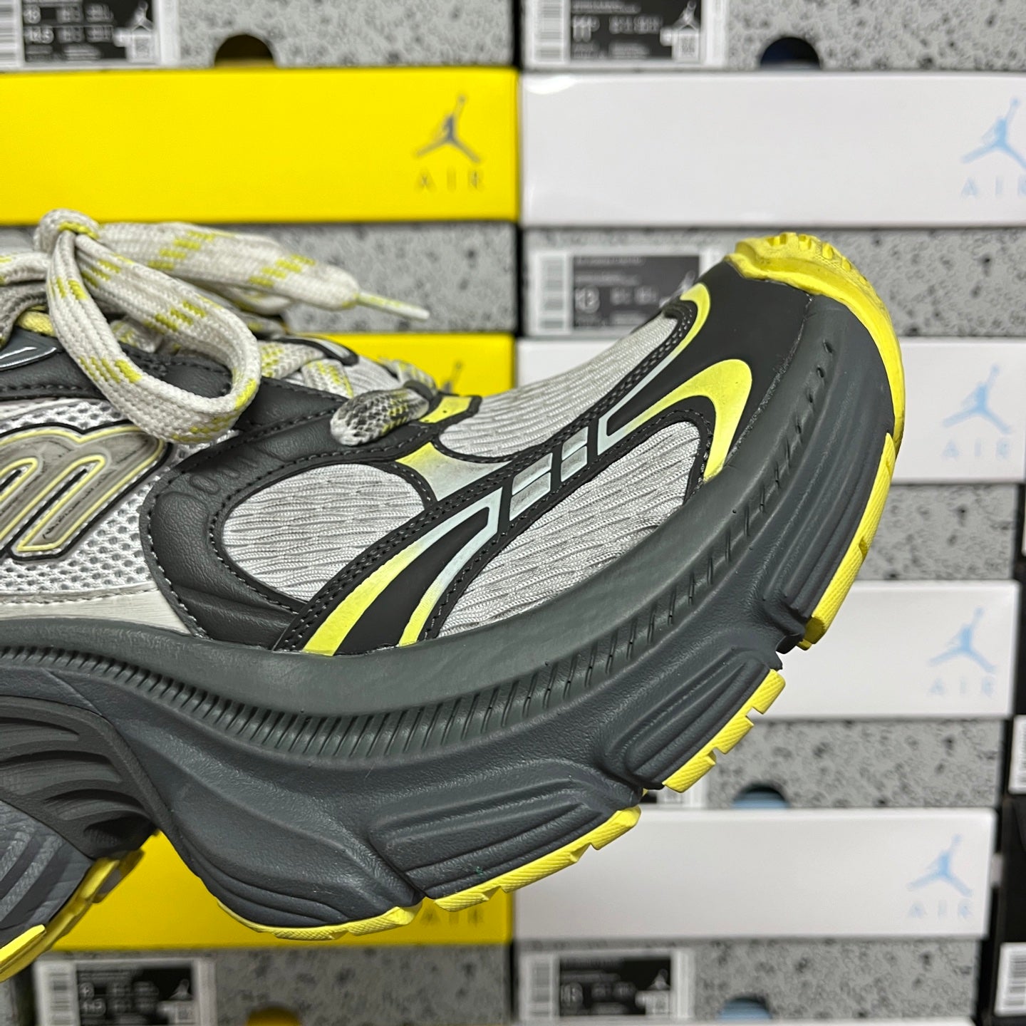 Quarter view lace-up sneaker in dark gray with neon yellow accents and textured sole.