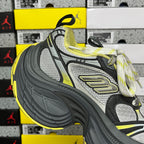 Front side lace-up sneaker in dark gray, silver-gray, and neon yellow with laces.