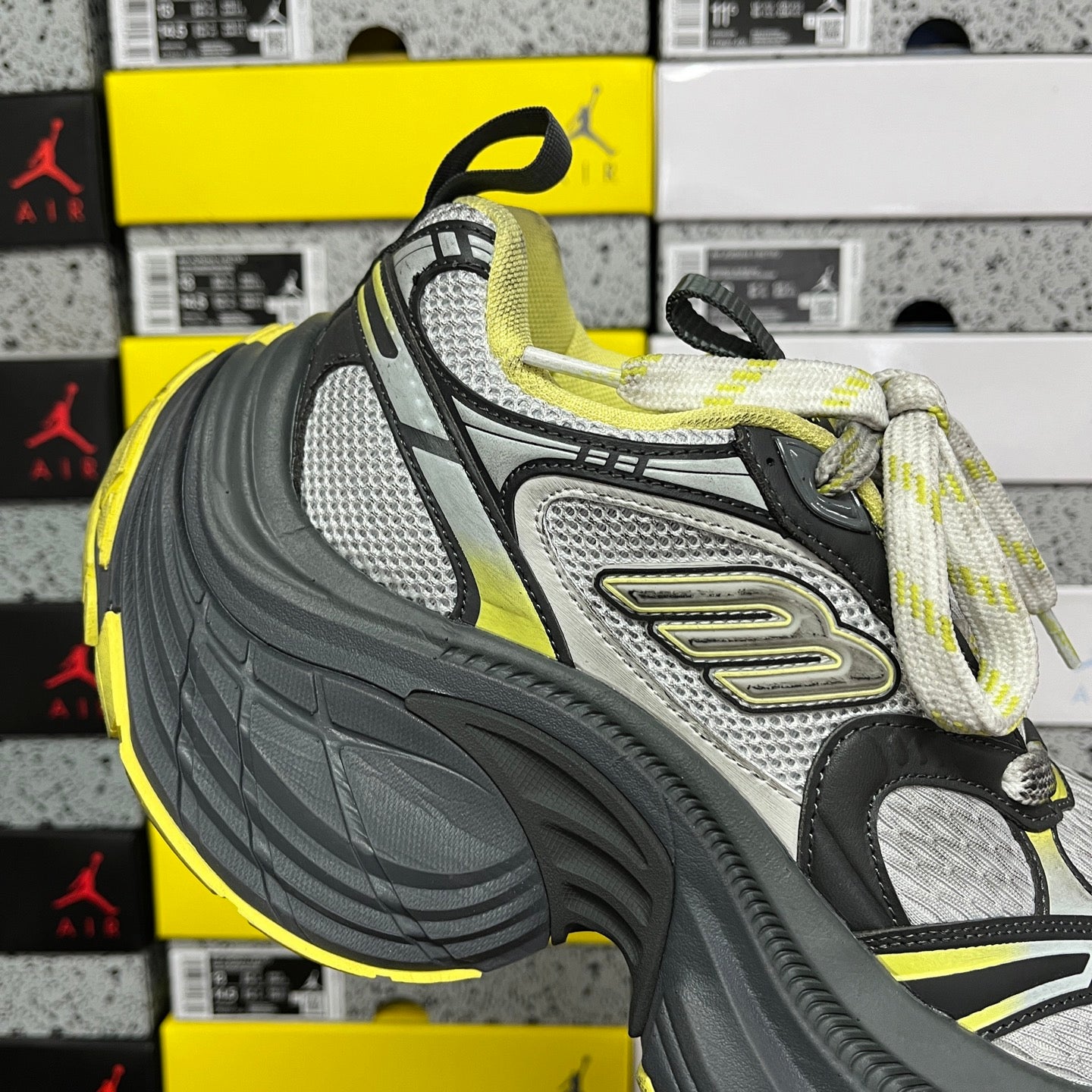 Front side lace-up sneaker in dark gray, silver-gray, and neon yellow with laces.